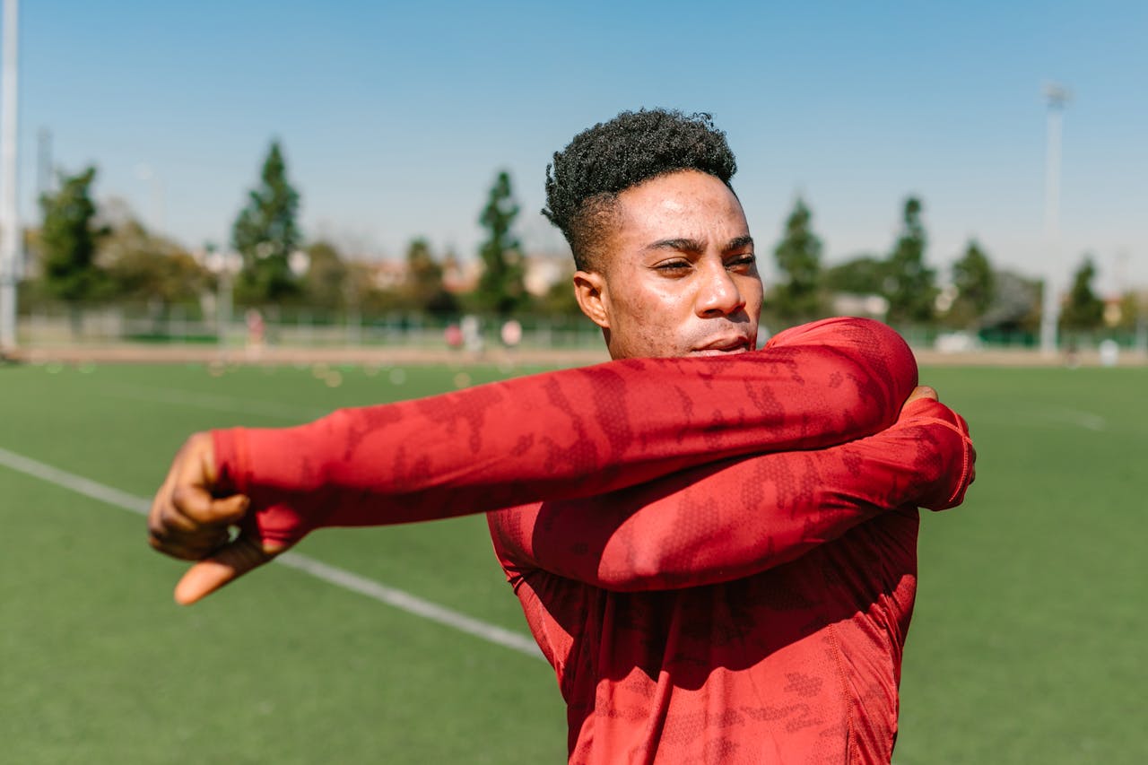 关于我们 African American man warming up outdoors with a stretch in sportswear on a sunny day.